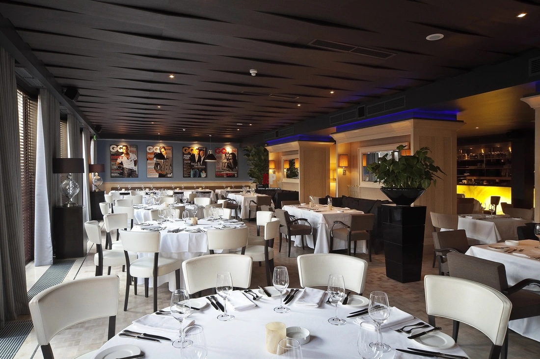 Интерьер европейского зала ресторана в стиле фьюжн. Потолок оформлен широкими панелями, которые располагаются в разных плоскостях.
