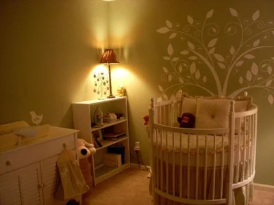 Комната для новорожденного. Симпатичное стилизованное деревце на стене возле кроватки крохи