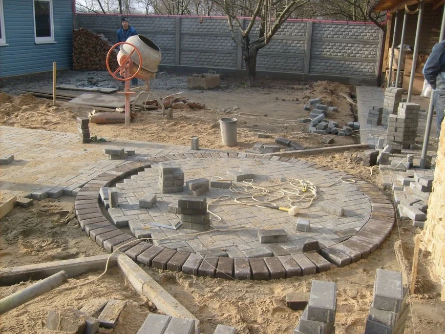 Мощение начинаем от центра площадки к краям. При мощении следите, чтобы плитка или брусчатка выступала не менее чем на 3 см выше уровня песка.